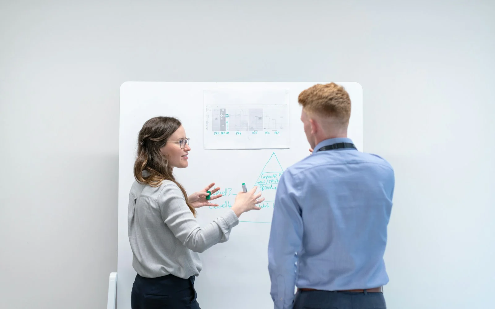 Dois colegas discutindo ideias diante de um quadro branco