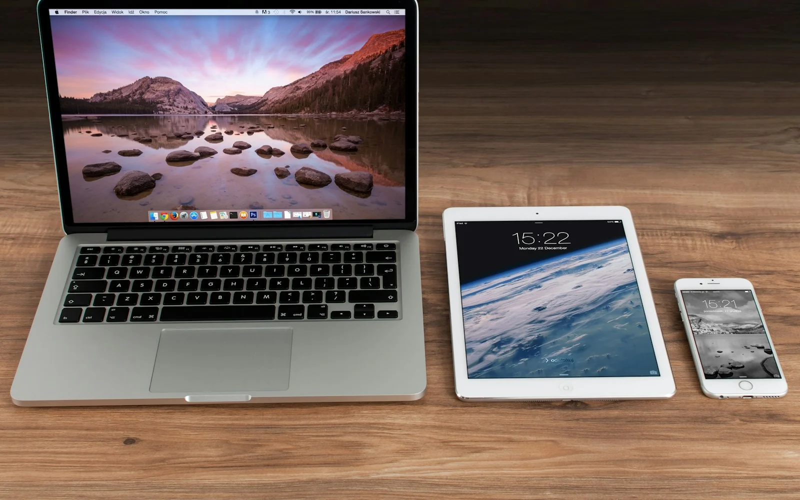 Notebook, tablet e celular lado a lado sobre uma mesa de madeira