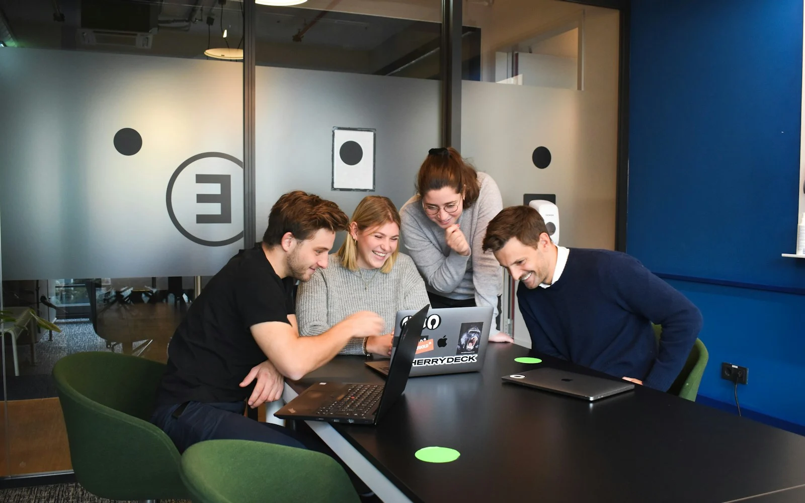 Equipe sorrindo em volta de um notebook em uma sala de reunião
