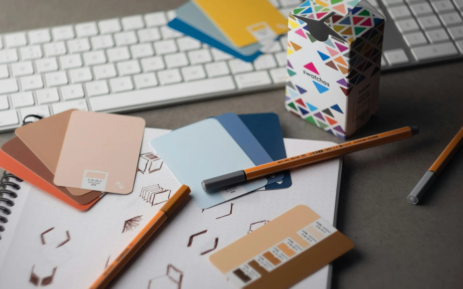 Amostras de cores, lápis e materiais de identidade visual sobre uma mesa
