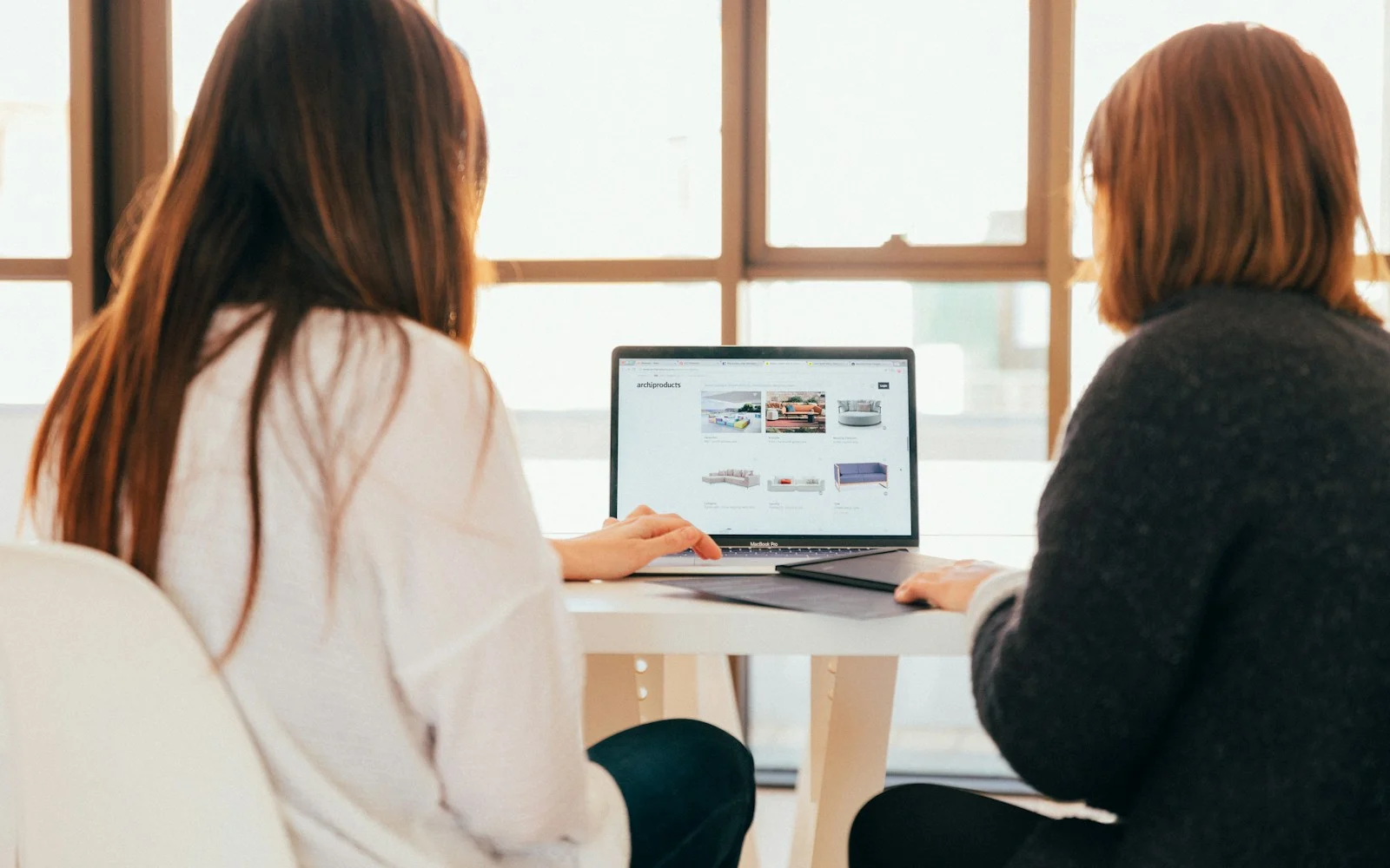 Duas mulheres conversando enquanto olham para a tela de um notebook