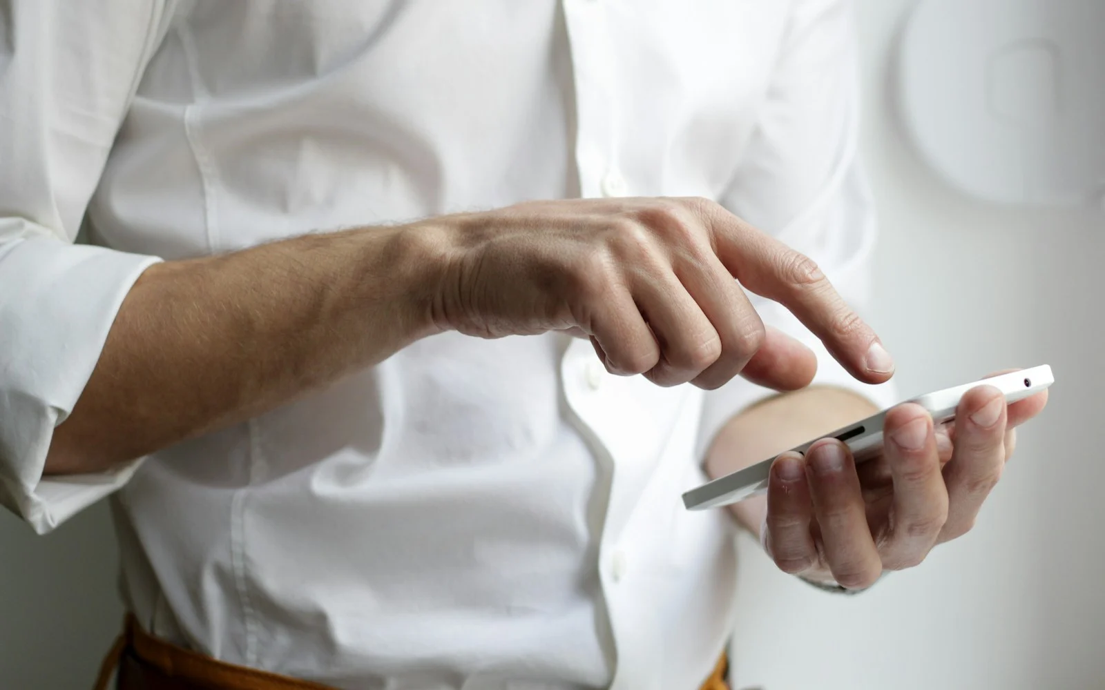 Homem de camisa branca digitando uma mensagem no celular