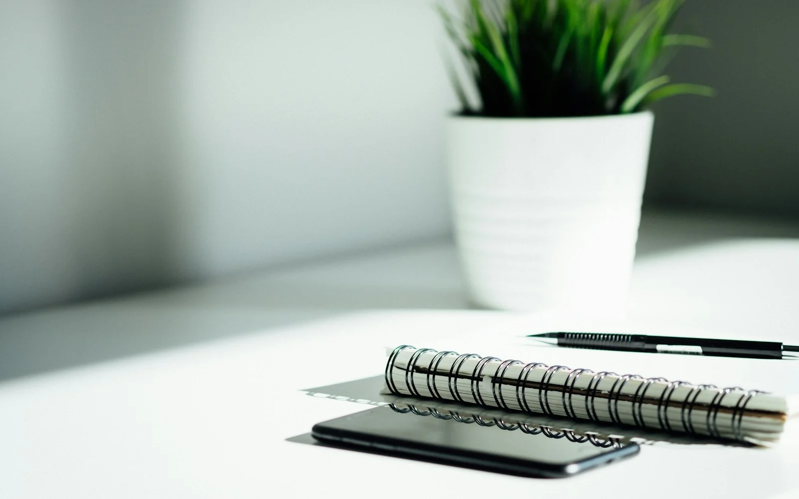 Caderno, caneta e celular sobre uma mesa organizada